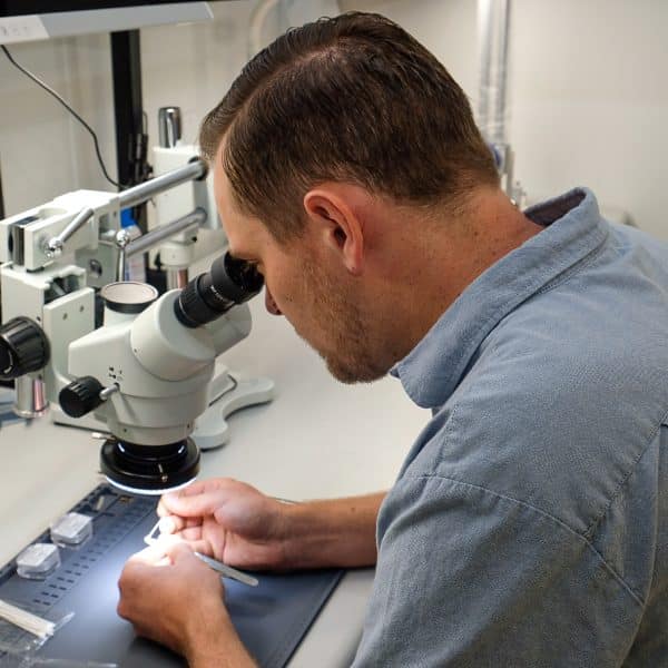 Man looking at materials through microscope on desk
